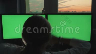 金发少女将双手举到粉红色日落背景下的绿色大屏幕显示器前